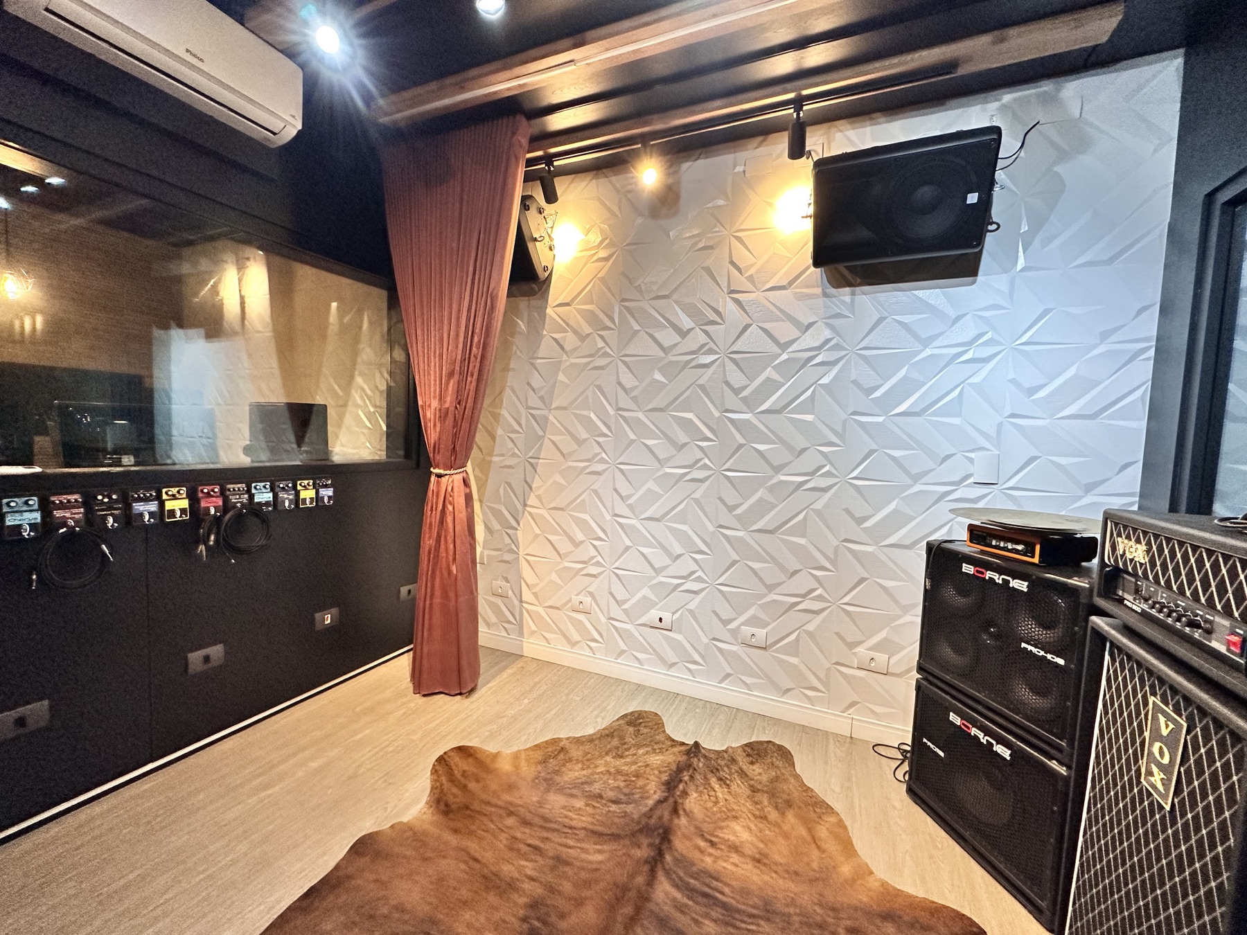 Sala de ensaio com tratamento acústico, amplificadores e pedais de guitarra