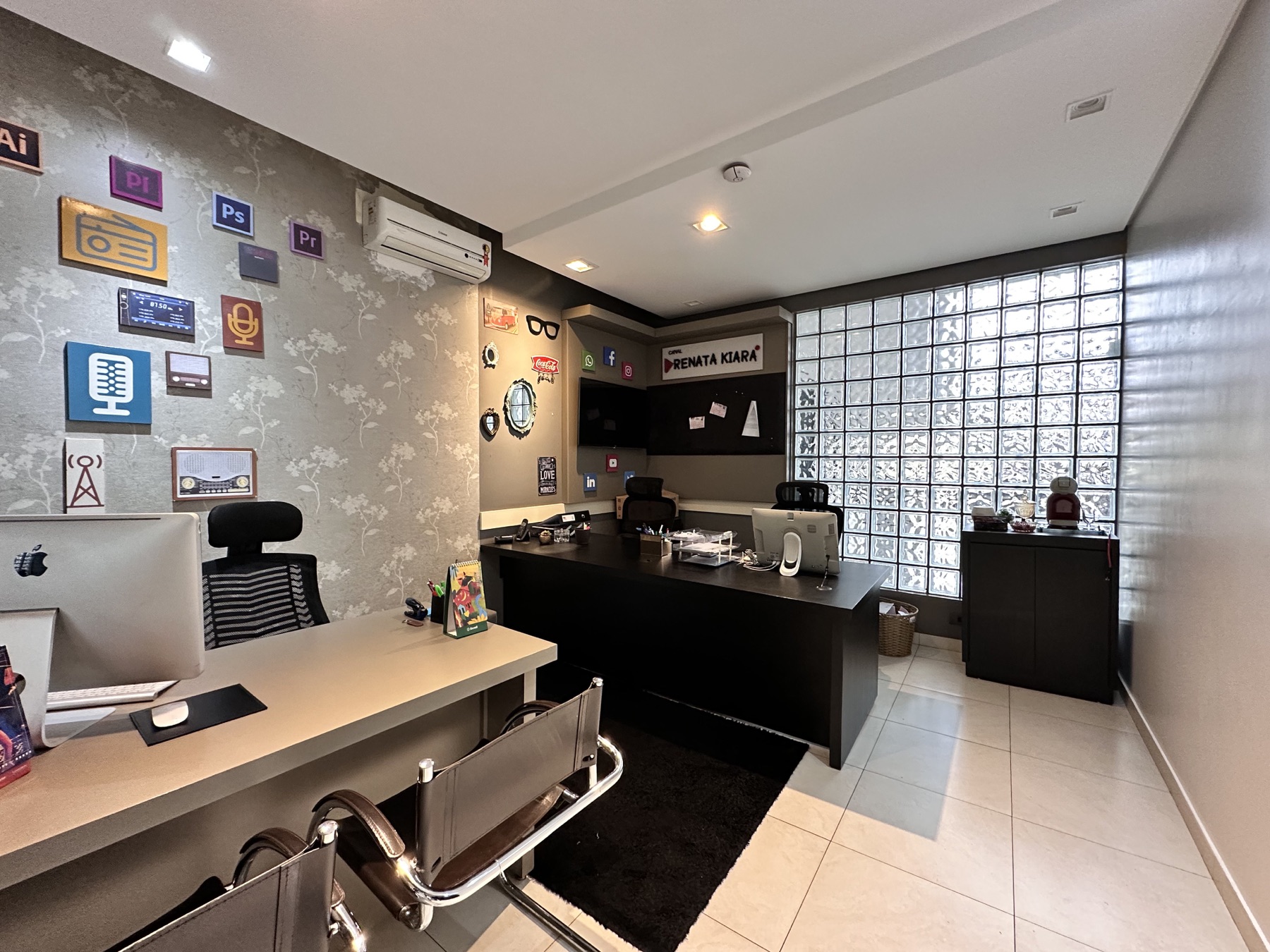 Sala de criação e atendimento com estações de trabalho e parede decorada com ícones de rádio e mídia